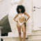 Woman in a white bikini standing on stone steps with a decorative wall in the background
