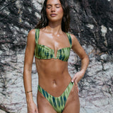 Woman wearing a green bikini against a rocky background