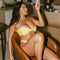 Woman in a yellow bikini taking a selfie in a kitchen.