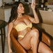 Woman in a yellow bikini taking a selfie in a kitchen.