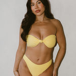 Woman wearing a yellow bikini against a plain background