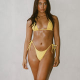 Woman wearing a yellow bikini standing against a plain background